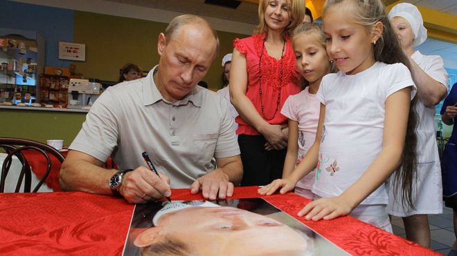 Bản quyền hình ảnh AFP Image caption Ông Vladimir Putin ký tên trên ảnh của chính mình để tặng học sinh trong chuyến đến thăm một trường học ở Khabarovsk hồi 2010, khi ông làm thủ tướng Nga. Qua các nhiệm kỳ thủ tướng và tống thống, ông Vladimir Putin rất chú ý tới hình ảnh 'gần dân' nhưng gần đây số người tin ông giảm đi.