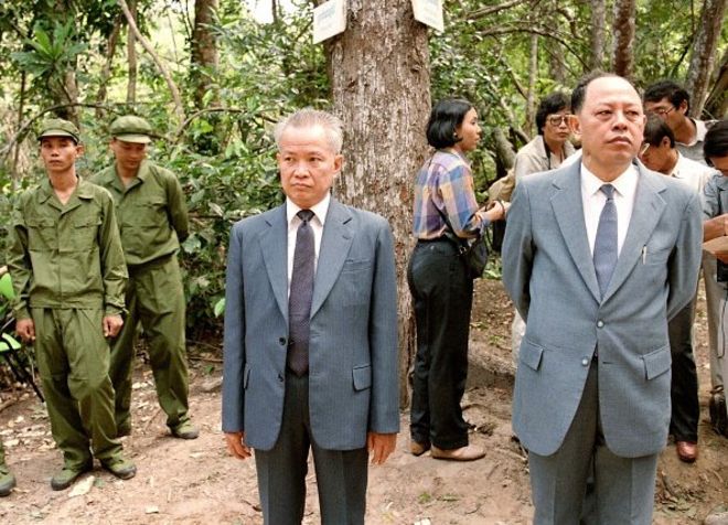 Khieu Samphan (giữa), Phó Chủ tịch Chính quyền Liên minh của Kampuchea Dân chủ và Ieng Sary (phải), Bộ trưởng Ngoại giao, ăn mặc đẹp để ra đón phái đoàn Trung Quốc ở căn cứ Dong Rek của Khmer Đỏ năm 1985. Ieng Sary, tên là Kim Trang, sinh ra ở Châu Thành, Trà Vinh trong gia đình cha là người Khmer, mẹ người Việt gốc Hoa